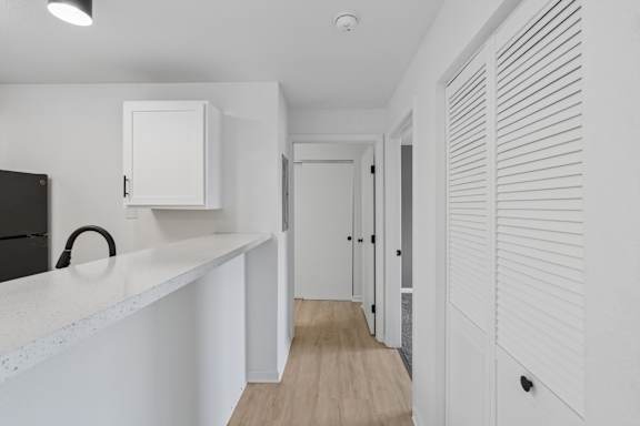 A white kitchen with a black fridge and a white cabinet.
