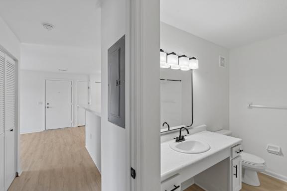 A white bathroom with a sink, mirror, and toilet.