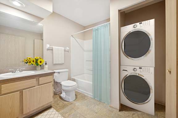 A modern bathroom with a washer and dryer built into the wall.