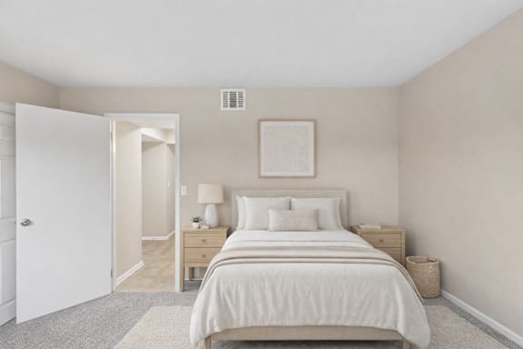 A bedroom with a large bed and a nightstand with a lamp.
