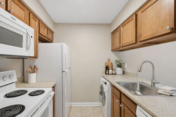 A kitchen with white appliances and wooden cabinets.