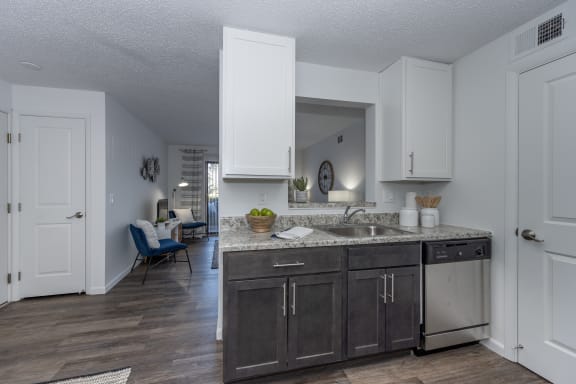 an open kitchen and living room with white cabinets and a sink