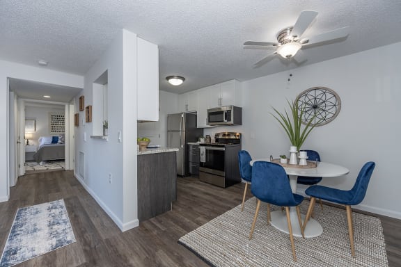 a living room and kitchen with a table and chairs and a ceiling fan