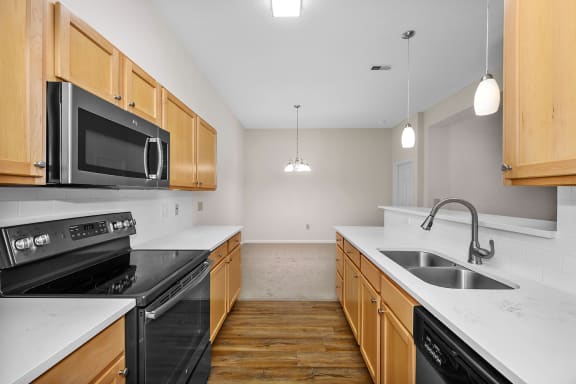 a kitchen with wood cabinets and black appliances and white counter tops at Bishops Gate, Cincinnati, OH