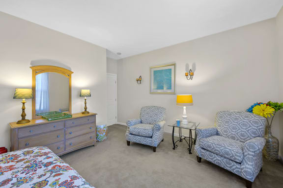 a bedroom with a bed and two chairs and a dresser at Bishops Gate, Cincinnati, OH