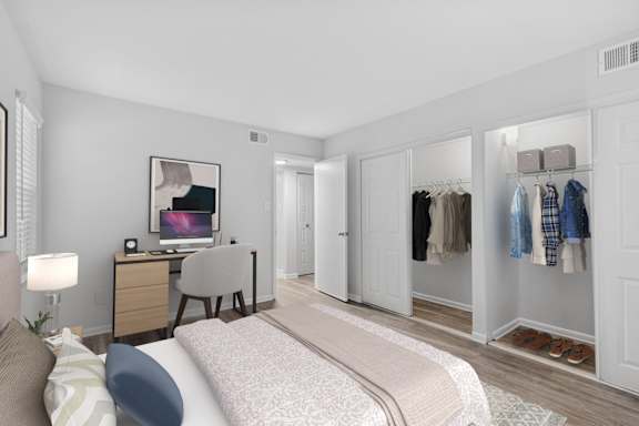 A bedroom with a bed, desk, chair, and closet.