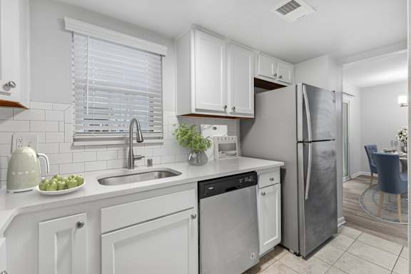 A modern kitchen with white cabinets and stainless steel appliances.