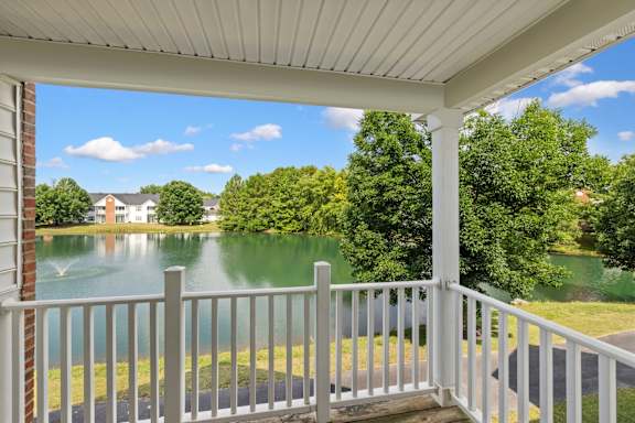 A porch with a view of a lake and houses.