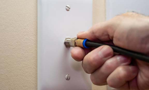 A person is screwing a light switch into a wall socket at Mallard Landing Apartments, Marion