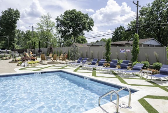 a swimming pool with chaise lounge chairs and a grassy area with trees in the background at Olde Towne in Kenwood, Ohio, 45243