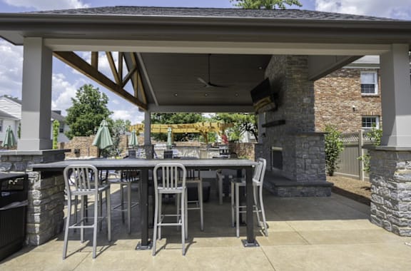 an outdoor kitchen with a bar and stools in front of a stone fireplace at Olde Towne in Kenwood, Ohio, 45243