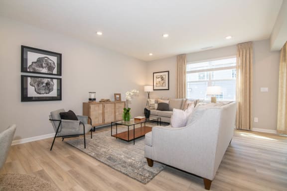 a living room with a couch and a chair in front of a window at Jackson Run Townhomes, Whitestown, IN 46075