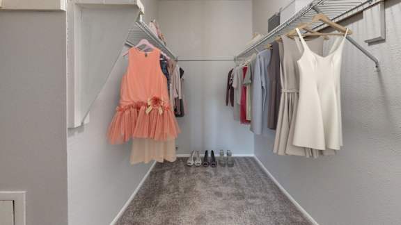 A row of dresses hanging on a rack in a room.