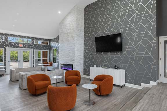 A modern living room with a grey patterned wall and orange chairs.
