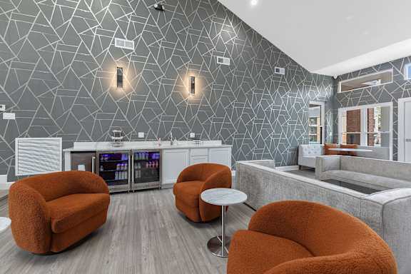 A modern living room with orange chairs and a grey wallpaper.