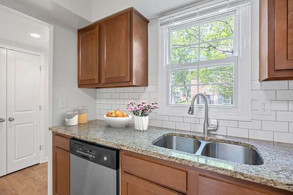 A kitchen with a dishwasher, sink, and wooden cabinets.