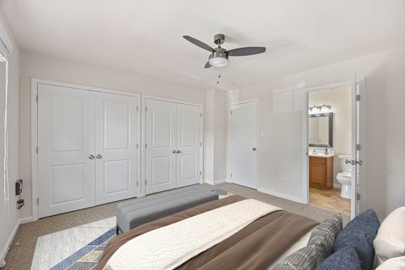 A bedroom with a bed, a ceiling fan, and a mirror.