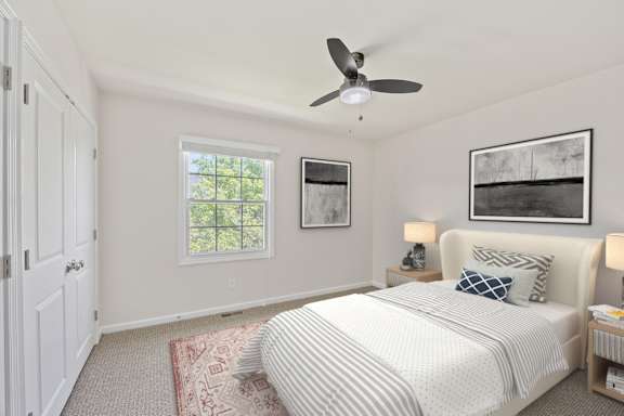 A bedroom with a large bed and a ceiling fan.