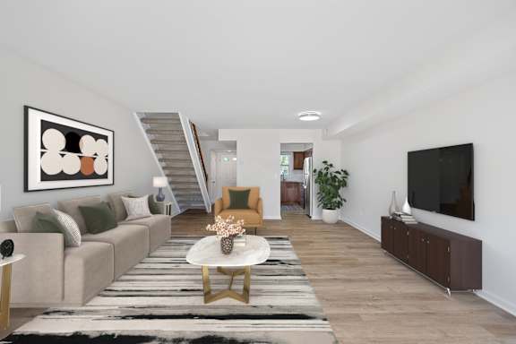 A living room with a grey couch, a coffee table, a staircase, and a television.