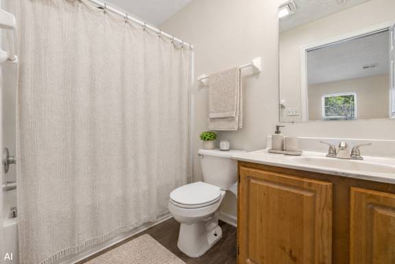 A white toilet sits in a bathroom with a beige shower curtain.