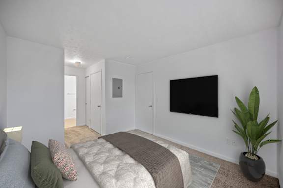 A bedroom with a bed, a couch, a plant, and a television.