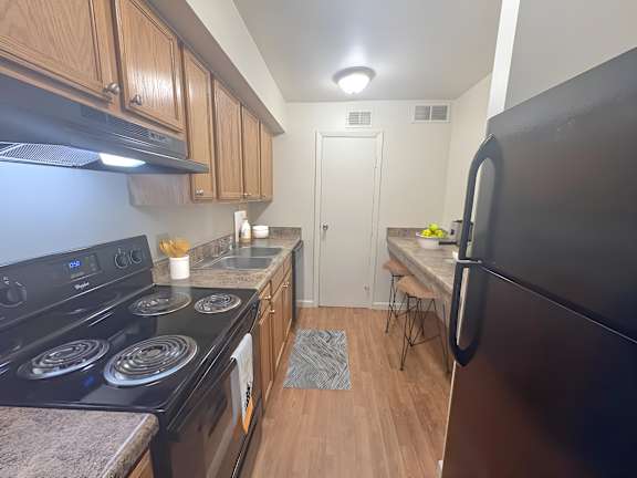 A kitchen with a black stove top oven and a black refrigerator.