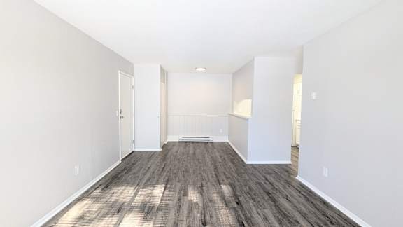 A spacious room with wooden flooring and white walls.
