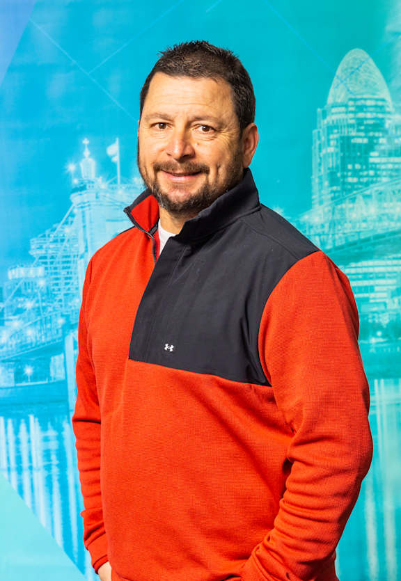 A man wearing a red and navy sweater with a black collar.