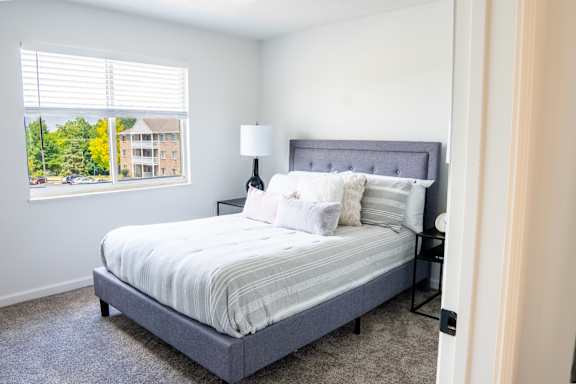 A bedroom with a bed, nightstand, and window.