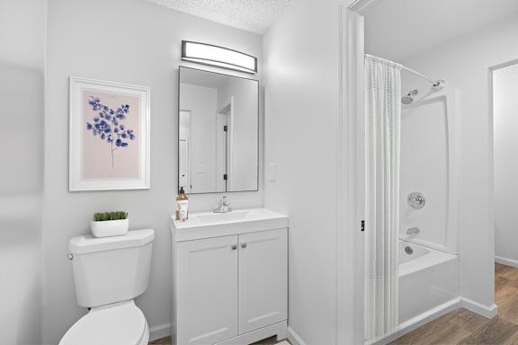 A white bathroom with a toilet, sink, and shower.