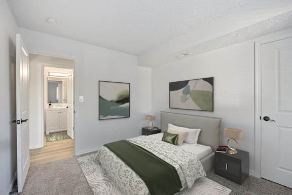 A bedroom with a bed, nightstand, and a painting on the wall.