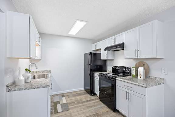 A kitchen with white cabinets and a black refrigerator.