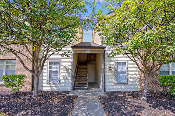 A house with a grey facade and a tree in front.