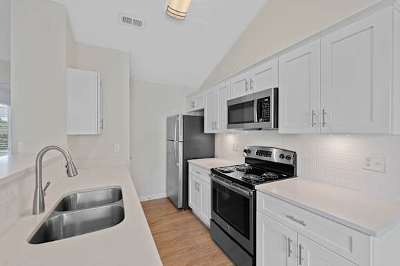 A kitchen with white cabinets and black appliances.