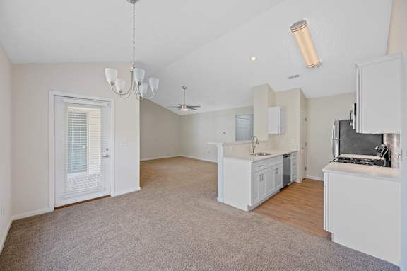 A spacious kitchen with white cabinets and a grey carpet.