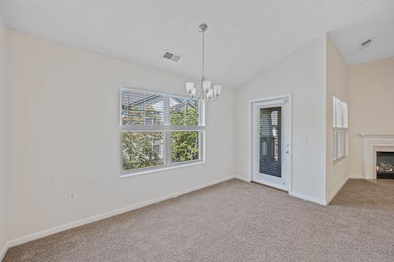 A room with a carpet floor, a chandelier, and a fireplace.
