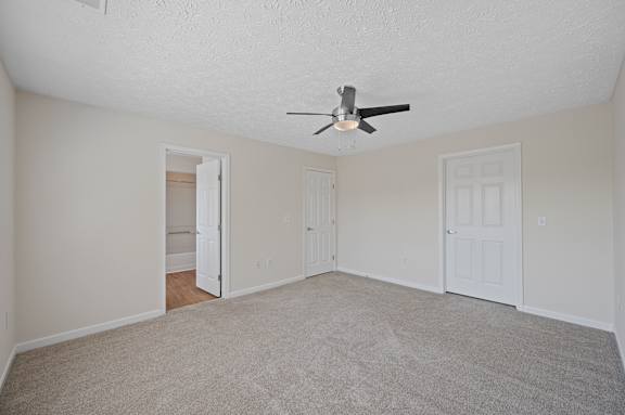 A room with a ceiling fan and carpeted floor.