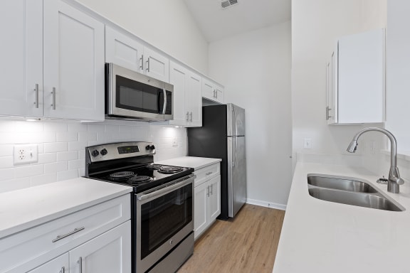 an all white kitchen with stainless steel appliances and white cabinets at Four Bridges, Liberty Township