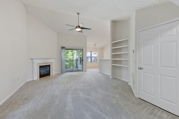 an empty living room with a fireplace and a ceiling fan at Four Bridges, Liberty Township, OH