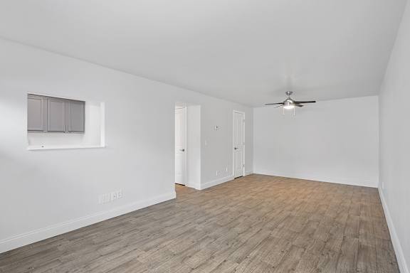 A room with a ceiling fan and wooden flooring.
