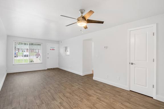A room with a ceiling fan and wooden flooring.