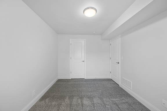 A room with a carpeted floor and two white doors.