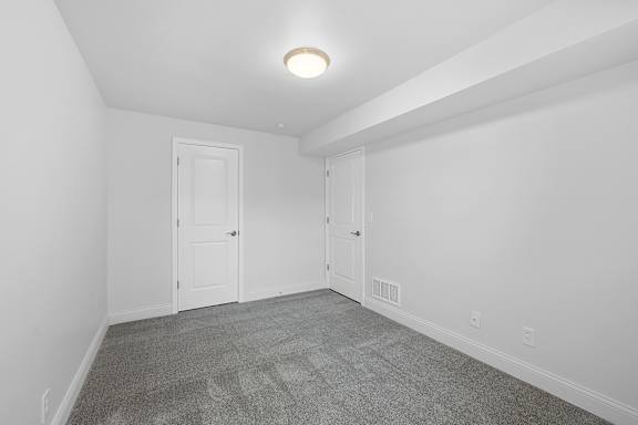 A room with a carpeted floor and two doors.