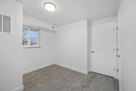 A white door is open in a room with a carpeted floor.