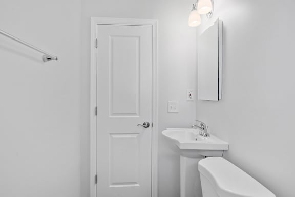 A white bathroom with a toilet, sink, and mirror.