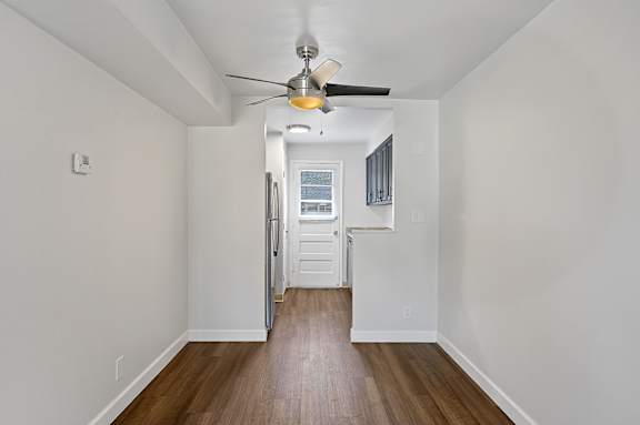 A room with a ceiling fan and wooden floors.