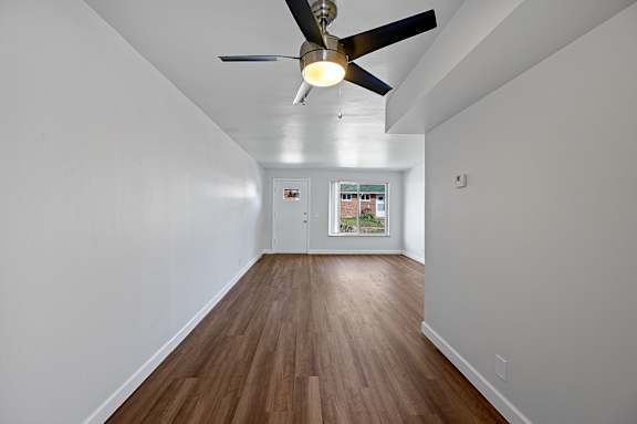 A room with a ceiling fan and wooden flooring.