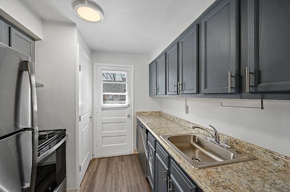 A kitchen with a sink, refrigerator, and cabinets.
