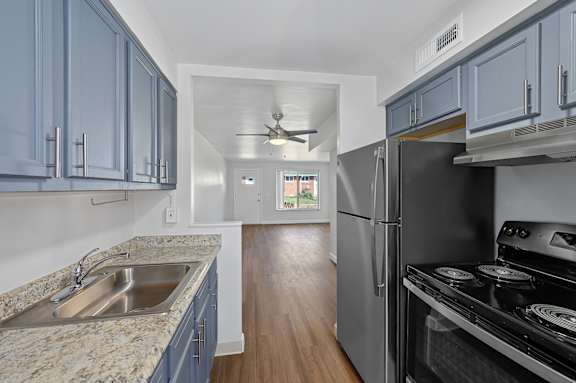 A kitchen with a sink, stove, and refrigerator.