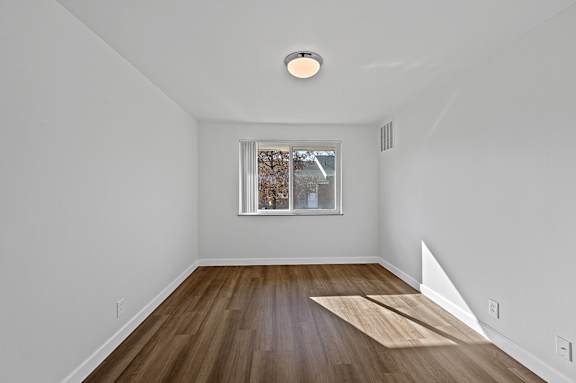 A room with a window and a wooden floor.